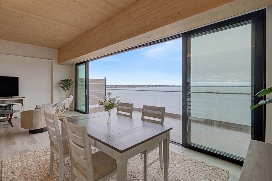 The dining table beside the opened sliding glass wall, with Muskegon Lake stretching beyond the balcony