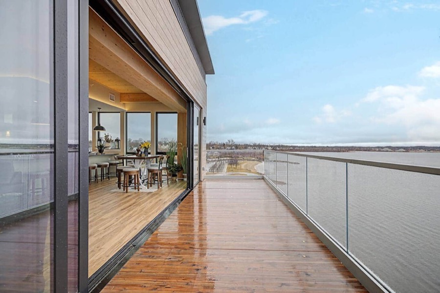 Long private balcony of the Above the Marina penthouse with glass railings, overlooking the shoreline of Muskegon Lake