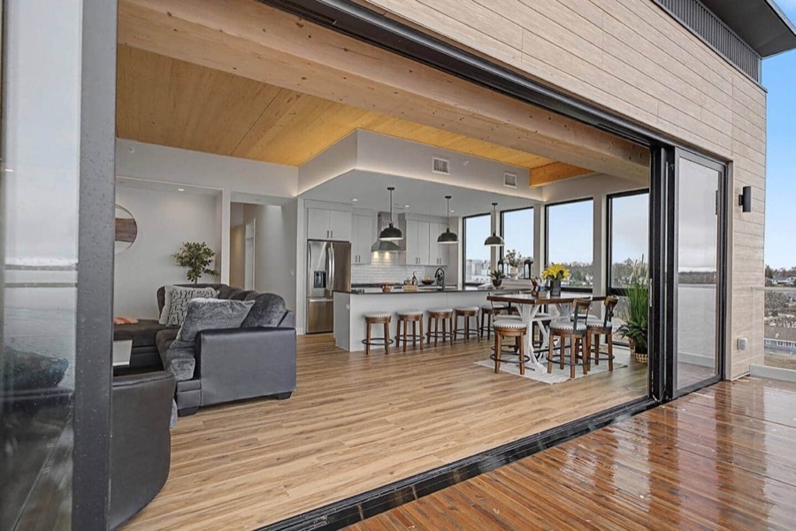 The floor-to-ceiling glass wall slid fully open, joining the living and dining space to the private balcony