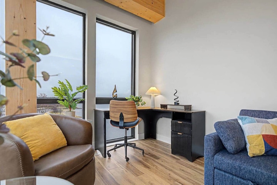 The dedicated lake-view office nook — desk and task chair beside a leather armchair and the guest-room sofa