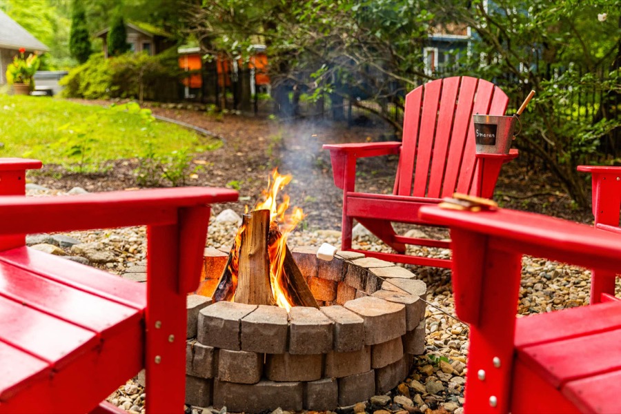 Marshmallows roasting over the stone fire pit, ringed by bright red Adirondack chairs with a s'mores bucket at the ready