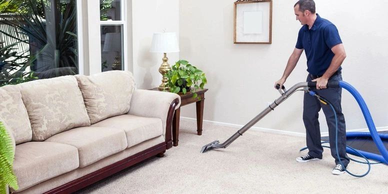 Technician steam cleaning a residential living room carpet