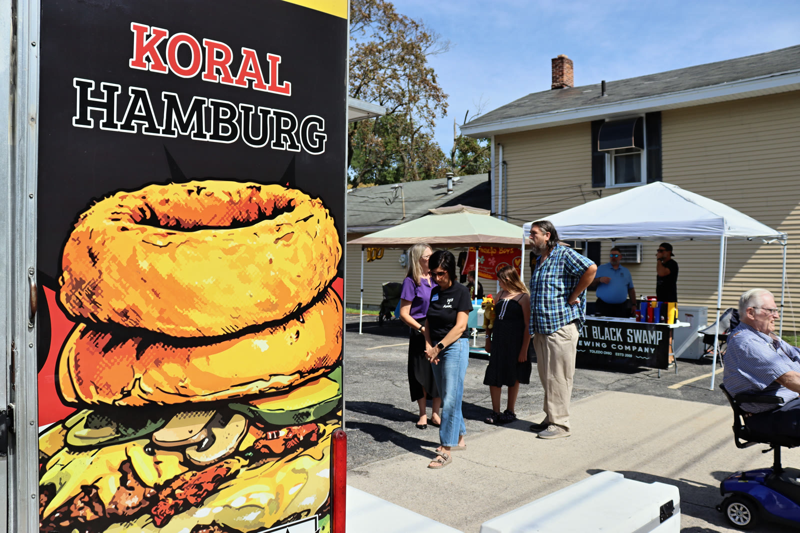 The back of the Koral Hamburg truck with its Kardiac Burger artwork, parked beside vendor tents at the 100-year celebration